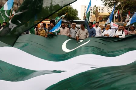 People wave a Kashmiri flag during a rally in solidarity with the people of Kashmir, in Karachi