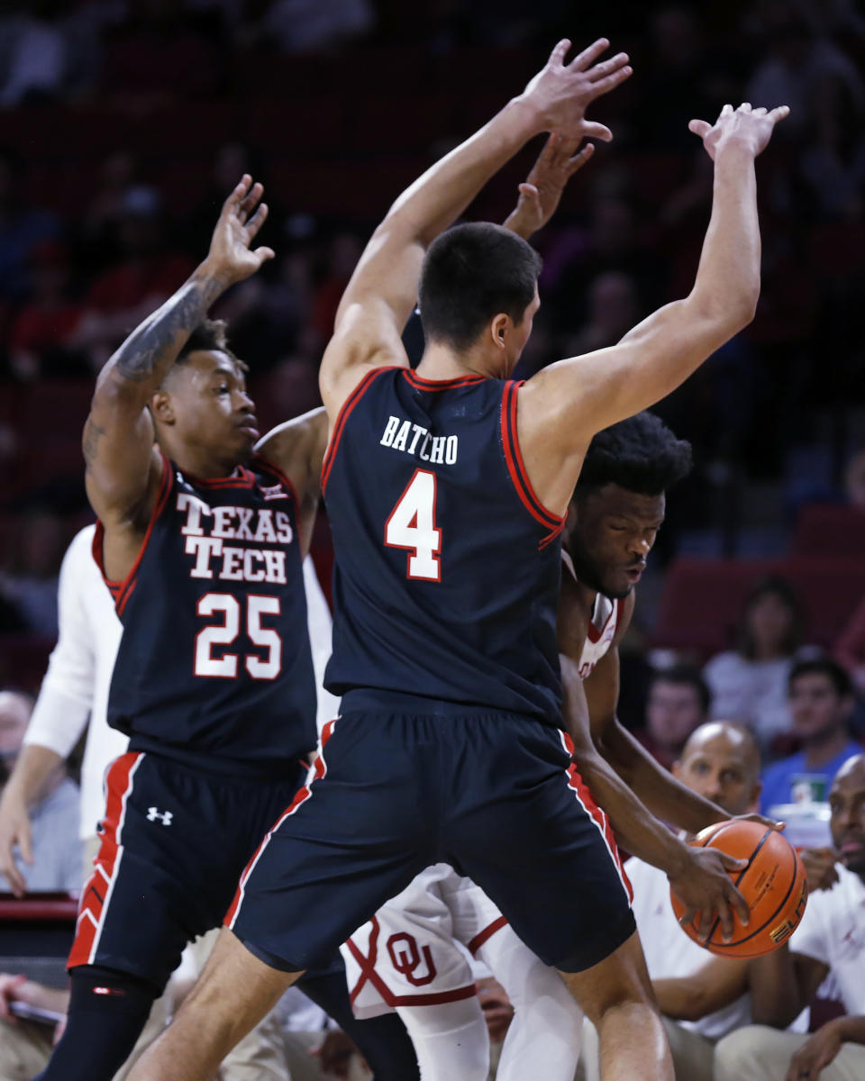 Oklahoma guard Elijah Harkless (55) is guarded by Texas Tech forward Daniel Batcho (4) and guard Adonis Arms (25) during the second half of an NCAA college basketball game Wednesday, Feb. 9, 2022, in Norman, Okla. (AP Photo/Garett Fisbeck)
