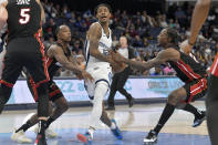 Memphis Grizzlies guard Ja Morant (12) drives between Miami Heat guards Jamaree Bouyea, second from left, and Marcus Garrett, right, in the second half of a preseason NBA basketball game Friday, Oct. 7, 2022, in Memphis, Tenn. (AP Photo/Brandon Dill)