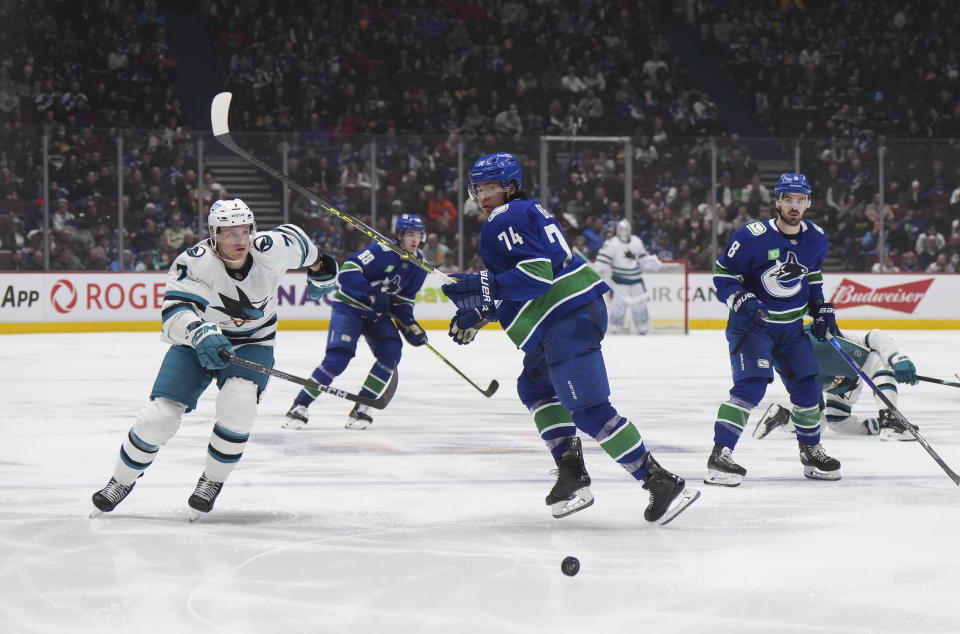 Vancouver Canucks' Ethan Bear (74) and San Jose Sharks' Nico Sturm, left, vie for the puck during the third period of an NHL hockey game in Vancouver, B.C., Thursday, March 23, 2023. (Darryl Dyck/The Canadian Press via AP)