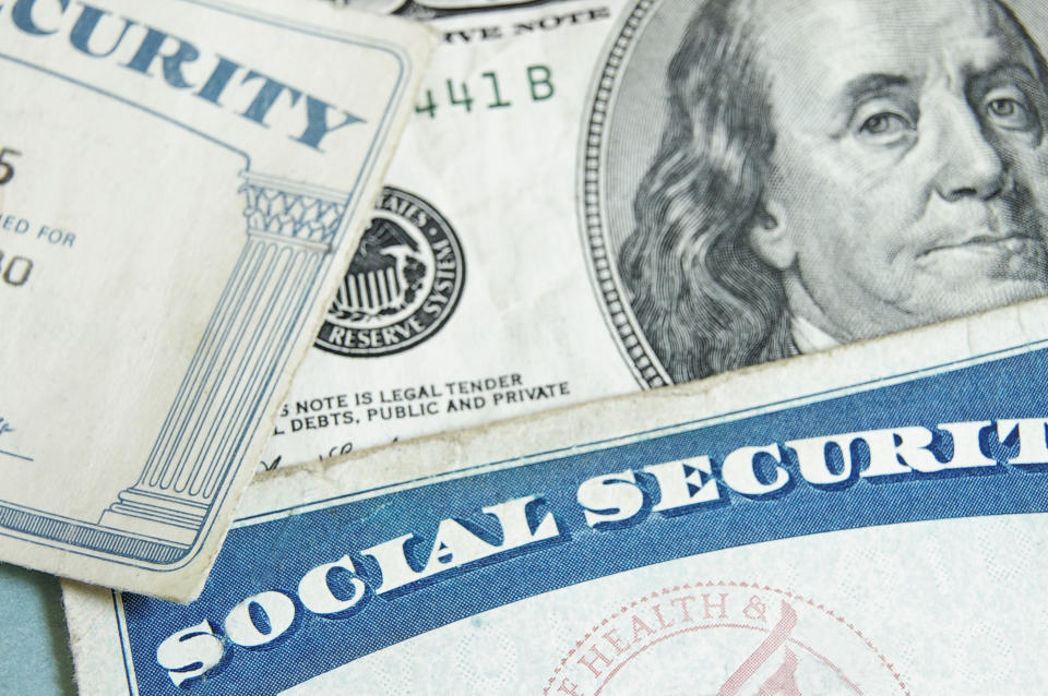 Two Social Security cards lying atop a hundred dollar bill.