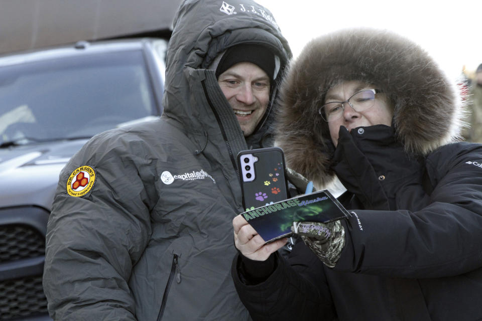 Five-time champion Dallas Seavey, left, takes a selfie with a fan before the ceremonial start of the Iditarod Trail Sled Dog Race Saturday, March 2, 2024, in downtown Anchorage, Alaska. The 1,000-mile race will take mushers and their dog teams a thousand miles over Alaska's unforgiving terrain, with the winner expected at the finish line in Nome, Alaska, in about 10 days. (AP Photo/Mark Thiessen)