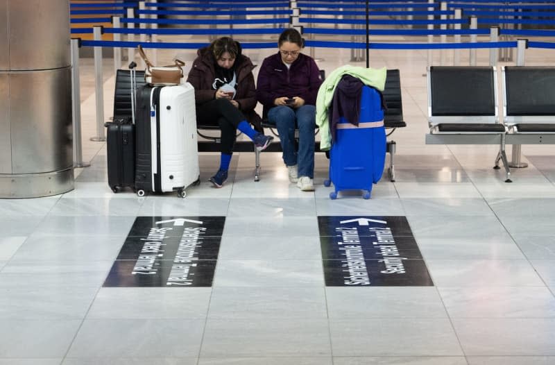 Two passengers who were originally due to fly from Stuttgart to Mexico, but whose flight was canceled due to the strike, sit on a bench in a terminal at Stuttgart Airport. Marijan Murat/dpa