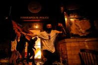 Protesters react as they set fire to the entrance of a police station as demonstrations continue in Minneapolis