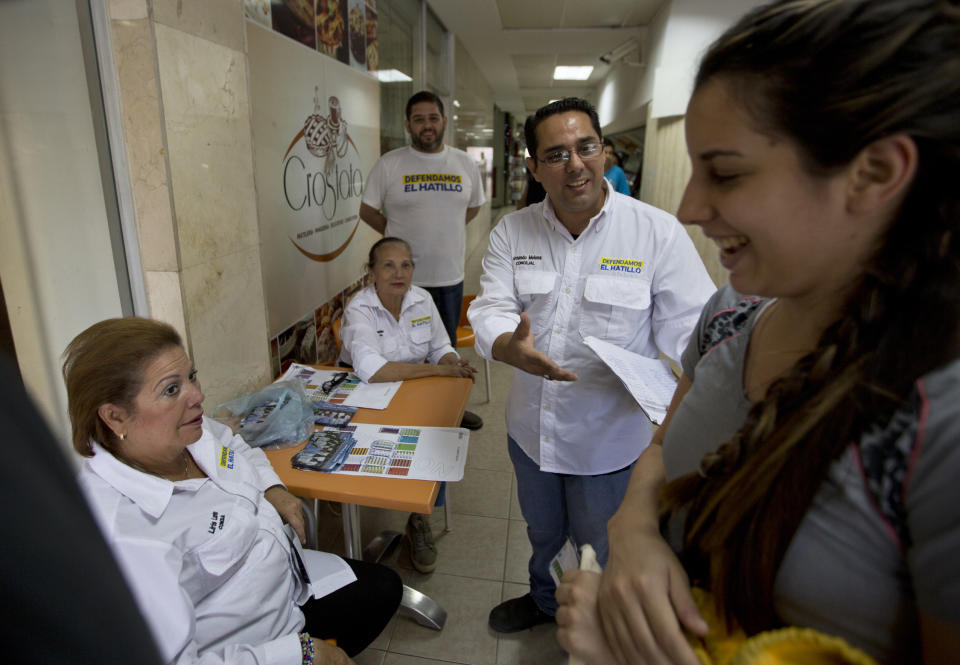 In this Dec. 5, 2018 photo, Fernando Melena, center, who is running to retain his council seat in the eastern district of El Hatillo, speaks with voters as he campaigns in the municipality of El Hatillo just outside Caracas, Venezuela. A handful of opposition candidates like Melena are throwing their names into the country's local council races on Dec. 9, trying to fill some 2,400 seats in elections boycotted by most parties protesting President Nicolas Maduro's rule. (AP Photo/Fernando Llano)