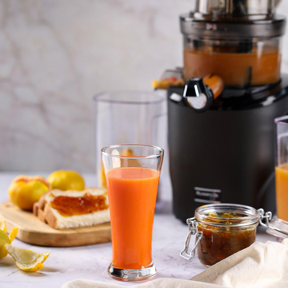 Image of UK Juicers press image of Kuvings jucier being used to make carrot juice, with carrot juice in shot