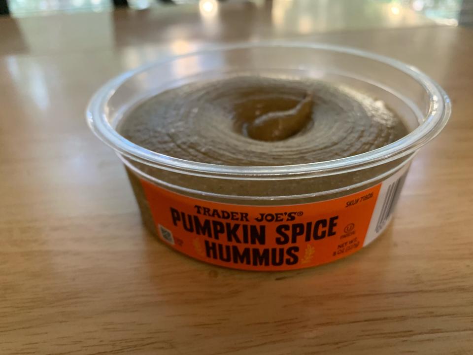 Clear container with orange label of Trader Joe's pumpkin-spice hummus on a wooden table