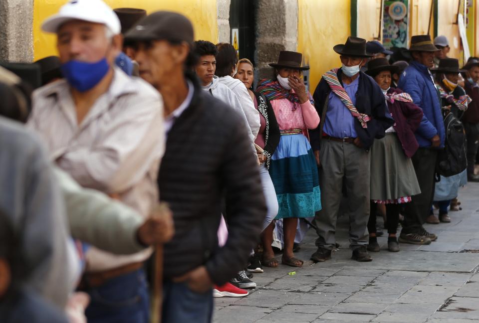 People wait in line to enter a bank in Ayacucho, Peru, Tuesday, Dec. 20, 2022. Peru's Congress is slated to consider a proposal on Tuesday to push up elections that have been a major demand of protesters blocking highways and clashing with security forces in deadly demonstrations across the country over the ouster of President Pedro Castillo. (AP Photo/Hugo Curotto)