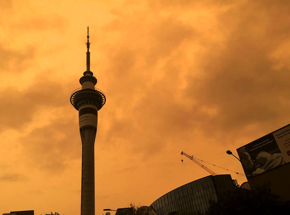 The sky above Auckland's Sky Tower turns orange as smoke from the Australia wildfires arrives in New Zealand, Sunday, Jan. 5, 2020. Australian Prime Minister Scott Morrison defended his leadership and his government's record on climate change Sunday as milder temperatures brought hope of a respite from wildfires that have ravaged three states, destroying almost 2,000 homes. (Luke Kirkness/New Zealand Herald via AP)