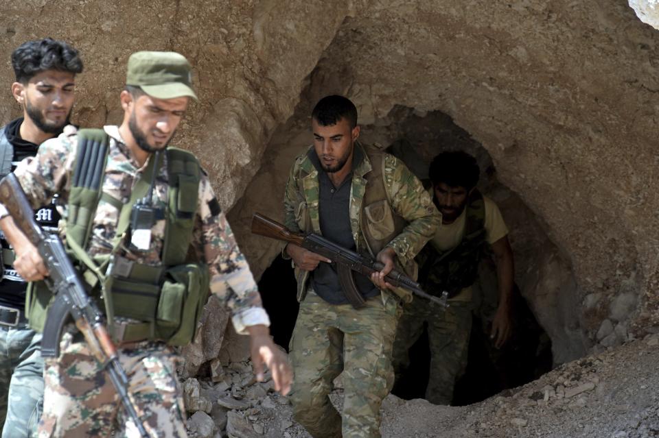 FILE - In this Sept. 9, 2018 file photo, fighters with the Free Syrian army exit a cave where they live, in the outskirts of the northern town of Jisr al-Shughur, Syria, west of the city of Idlib. After eight months of relative calm, Idlib is once again a theater for bloody military operations as Syrian government troops, backed by Russia, push their way into the rebel-held enclave in a widening offensive. The violence in May 2019 threatens to completely unravel a crumbling cease-fire agreement reached between Turkey and Russia last September. (Ugur Can/DHA via AP, File)