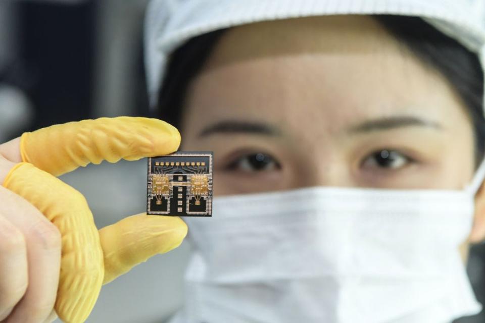 A woman in a mask holds up a microchip