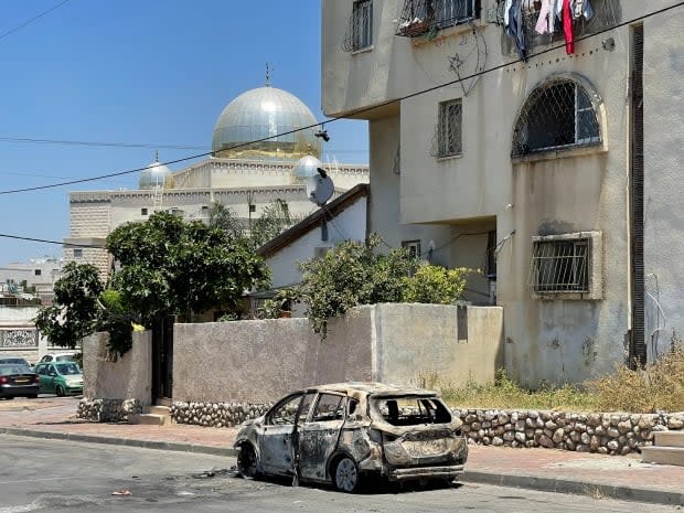 A burnt-out car sits on a street near a mosque in Lod, a mixed city in Israel, after violence broke out between Jewish and Arab Israelis last week. Rioting started after police ended a protest organized by Palestinian Arab Israelis over fighting between Israel and Palestinian militants in Gaza. (Stephanie Jenzer/CBC - image credit)