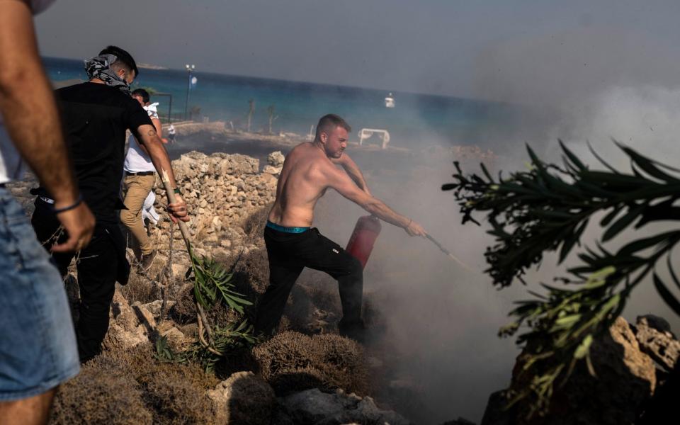 Local residents try to extinguish a fire, near the seaside resort of Lindos, on the Aegean Sea island of Rhodes, southeastern Greece, on Monday, July 24, 2023