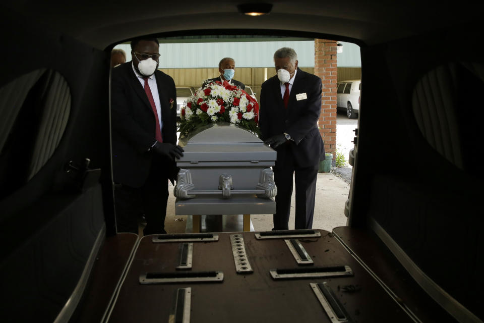 In this Saturday, April 18, 2020 photo, mortician Cordarial O. Holloway, foreground left, funeral director Robert L. Albritten, foreground right, place a casket into a hearse in Dawson, Ga. In a Feb. 25-March 1, 2021 poll conducted by The Associated Press-NORC Center for Public Affairs Research, about 1 in 5 Americans say they lost a relative or close friend to the coronavirus. (AP Photo/Brynn Anderson)