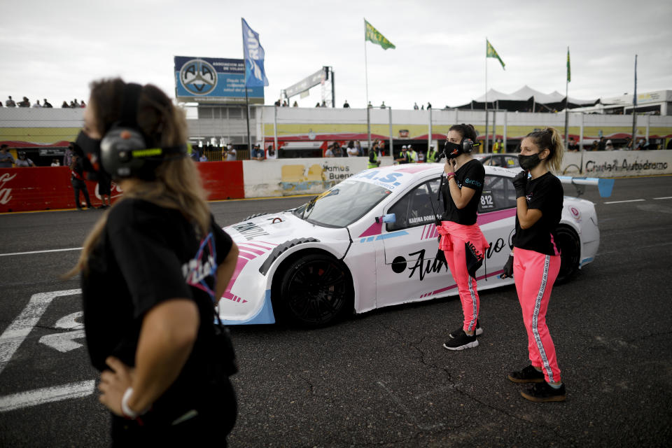 Vitarti Girl's Team mechanics Estenania Onofrio, left, Paula Salazar, center, and Victoria Pascual stand next to driver Karina Dobal before the start of their first race at the Oscar y Juan Galvez track in Buenos Aires, Argentina, Sunday, April 4, 2021. The women are part of the first entirely female team to take part in a national racing competition in Argentina. (AP Photo/Natacha Pisarenko)