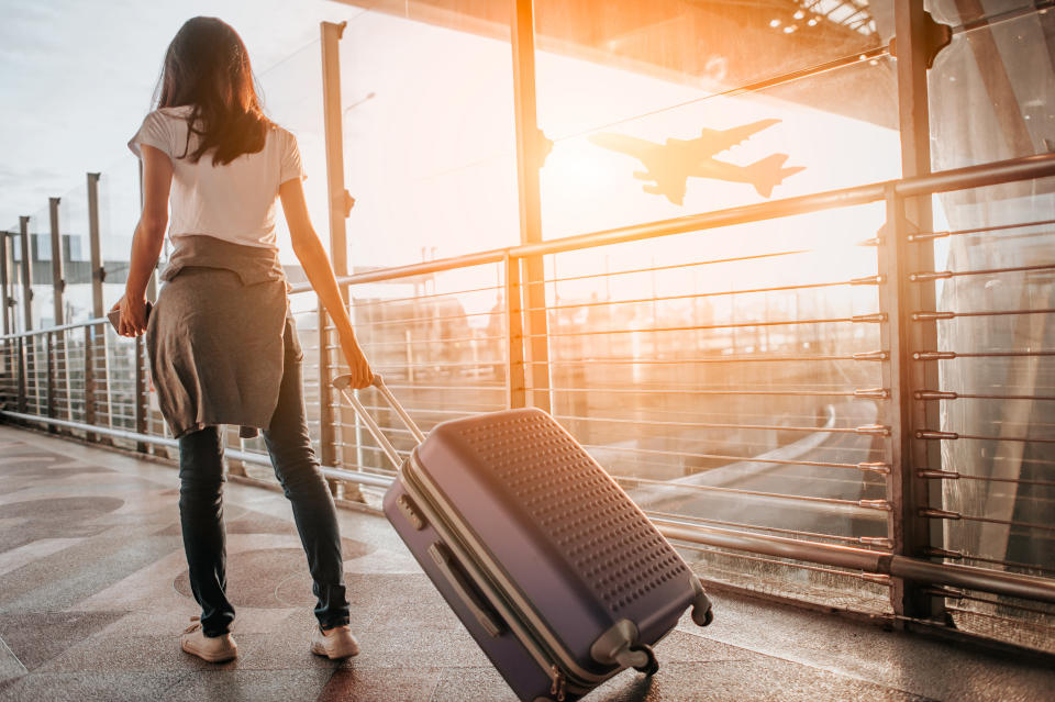 Young woman pulling suitcase in  airport terminal.