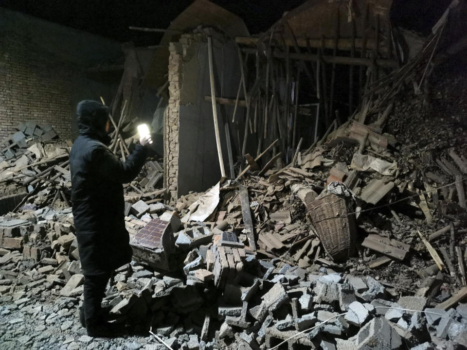 A government worker looks at the debris of a house brought down in the earthquake in Jishishan county in northwest China's Gansu province Tuesday, Dec. 19, 2023. At least 100 people were killed in a magnitude 6.2 earthquake in a cold and mountainous region in northwestern China, the country's state media reported on Tuesday. (Chinatopix Via AP)