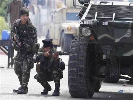 Government soldiers take cover beside an armoured vehicle during a firefight with Muslim rebels, on the fourth day of a government stand-off with the Moro National Liberation Front (MNLF) rebels in downtown Zamboanga city in southern Philippines September 12, 2013. REUTERS/Erik De Castro