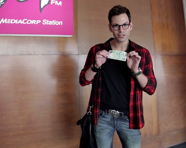 987FM deejay Bobby Tonelli poses with a $5 note, which he used in a day-long challenge. (Video screengrab)