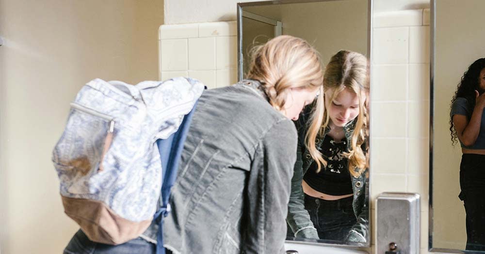 Photo of student washing hands in school bathroom, representing the new Biden policy protecting transgender students