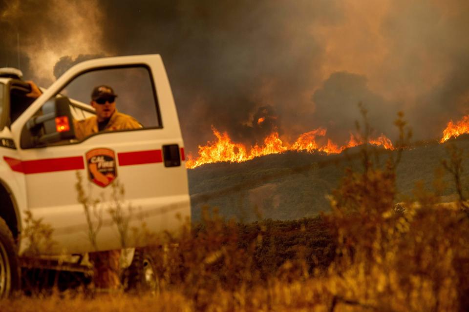 The Ranch fire, part of the Mendocino Complex fire, crests a ridge as Battalion Chief Matt Sully directs firefighting operations on High Valley Road near Clearlake Oaks, California, on Sunday. (Photo: NOAH BERGER via Getty Images)