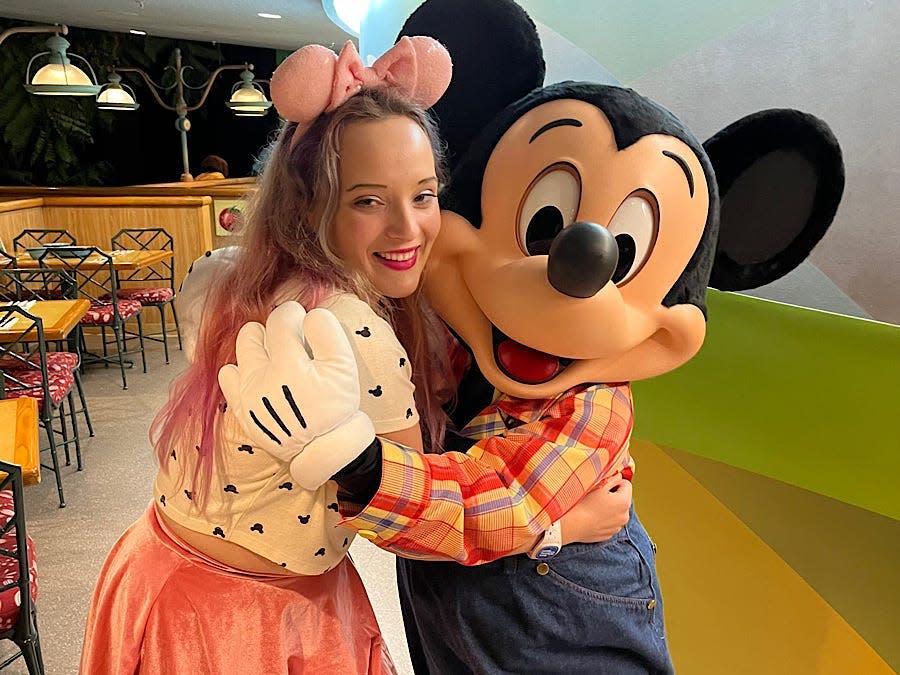 jenna posing with mickey mouse at garden grill in epcot at disney world
