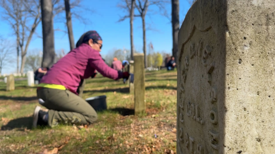 Volunteers clean graves at the Grand Rapids Veterans Home Cemetery on April 22, 2024.