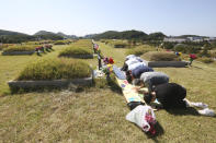 Family members bow to respect at their ancestral cemetery ahead of Chuseok holiday, the Korean version of Thanksgiving Day, at a cemetery in Paju, South Korea, Sunday, Sept. 27, 2020. South Korea's national cemeteries will be closed during the upcoming Chuseok holiday during the five-day holidays from Sept. 30 to Oct. 4 to prevent the spread of the coronavirus. (AP Photo/Ahn Young-joon)