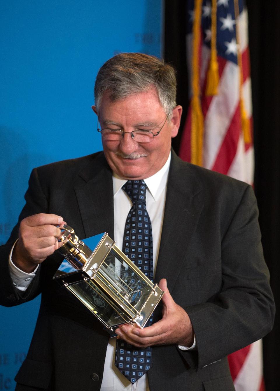 Paul W. Bridges, the former mayor of Uvalda, Ga., holds his 2014 John F. Kennedy Profile in Courage Award at the John F. Kennedy Library and Museum Sunday, May 4, 2014 in Boston. Bridges is being recognized for risking his mayoral career by publicly opposing a controversial immigration law. (AP Photo/Gretchen Ertl)