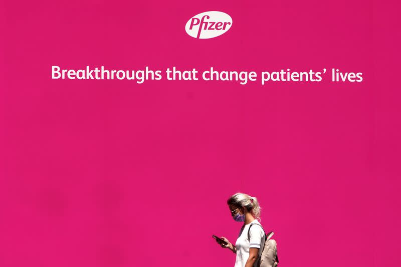 FILE PHOTO: A woman walks past a sign outside Pfizer Headquarters in the Manhattan borough of New York City