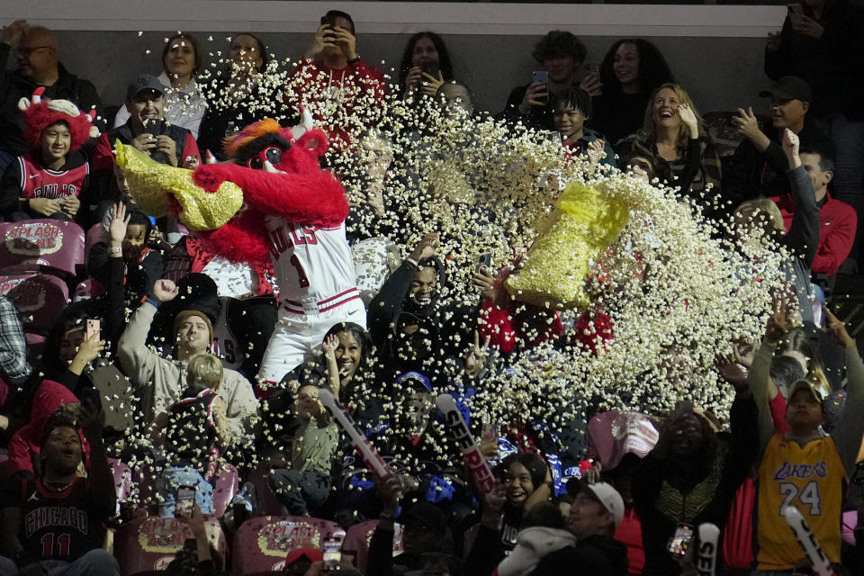 The Chicago Bulls mascot Benny The Bulls pours a complete bag of popcorn on fans during a break in the action in the first half of an NBA basketball game between the Bulls and the Utah Jazz Monday, Nov. 6, 2023, in Chicago. (AP Photo/Charles Rex Arbogast)