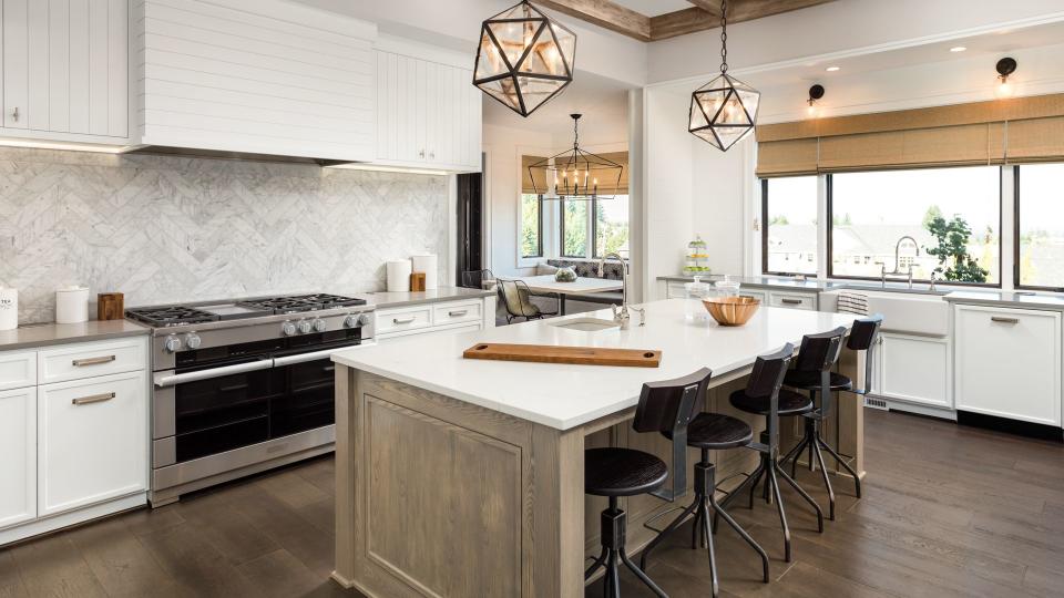 Kitchen Interior with Island, Sink, Cabinets, and Hardwood Floors in New Luxury Home.