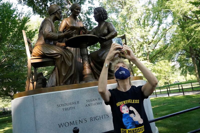 Woman takes a selfie in-front of a bronze statue in Manhattan's Central Park