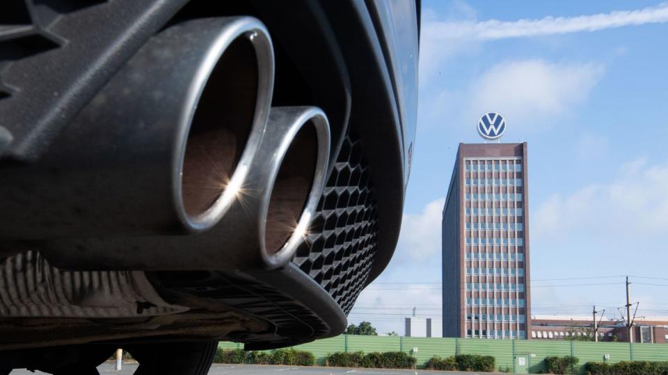 Auspuffrohre eines Volkswagen, fotografiert mit dem Markenhochhaus am VW Werk Wolfsburg. (Archivbild)