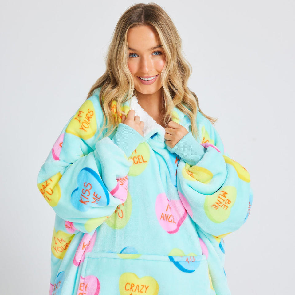 Woman with long blond hair wears a pastel patterned The Love Heart Candies Oodie, $84