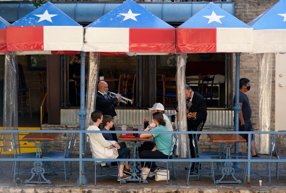 Mariachi perform for diners at a restaurant on the River Walk on Wednesday in San Antonio. Gov. Greg Abbott says Texas is lifting a mask mandate and lifting business capacity limits next week.