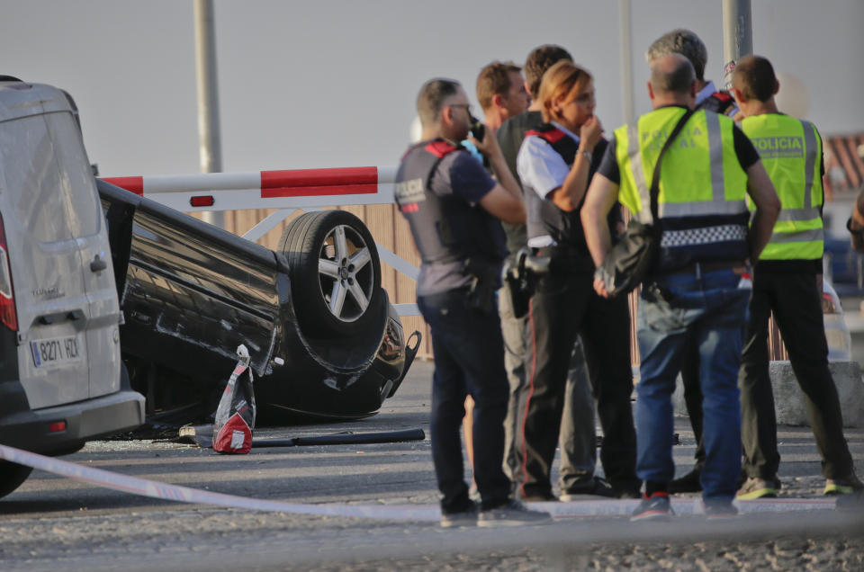 Police officers speak near an overturned car at the spot where terrorists were intercepted by police in Cambrils. (AP Photo/Emilio Morenatti)