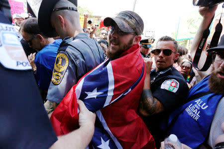 Police, clergy and free speech observers protect a man wearing a Confederate flag as a cape after he was surrounded by counter-protesters prior to the arrival of members of the Ku Klux Klan to rally in opposition to city proposals to remove or make changes to Confederate monuments in Charlottesville, Virginia, U.S. July 8, 2017. REUTERS/Jonathan Ernst