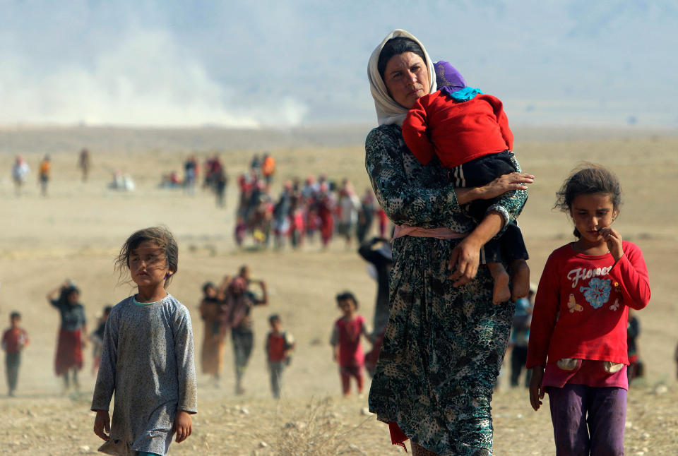 Displaced people from the minority Yazidi sect, fleeing violence from forces loyal to the Islamic State in Sinjar town, walk towards the Syrian border on the outskirts of Sinjar mountain near the Syrian border town of Elierbeh of Al-Hasakah Governorate in this August 11, 2014.&nbsp;
