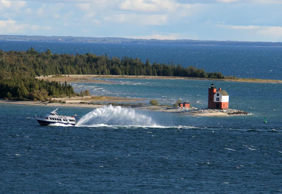 This Sept. 23, 2012 photo shows the ferry to Mackinac Island, Mich., and the Round Island Lighthouse, which dates to the 1890s but is no longer a functioning lighthouse. The picturesque lighthouse once marked the channel between Round Island and Mackinac. The ferry brings visitors to Mackinac, a vacation destination known for Victorian charm in modern times. (AP Photo/Anick Jesdanun)