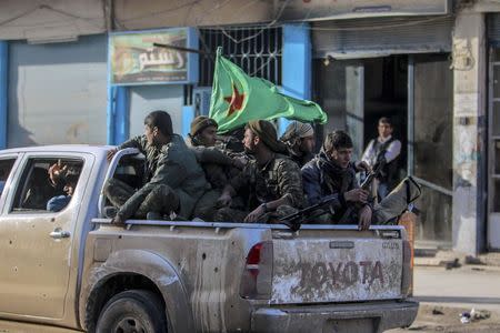 Fighters of the Kurdish People's Protection Units (YPG) carry their weapons along a street in the Syrian Kurdish city of Qamishli, in celebration after it was reported that Kurdish forces took control of the Syrian town of Tel Hamis, February 27, 2015. REUTERS/Rodi Said