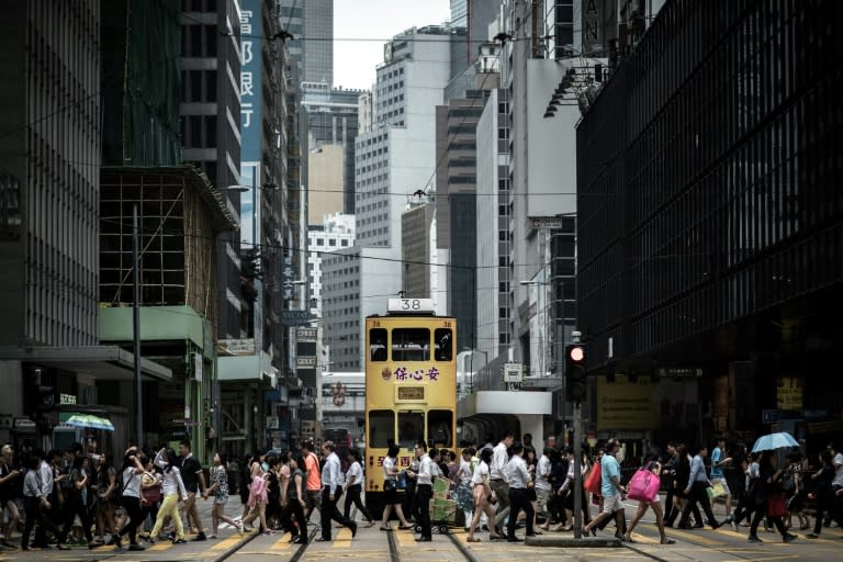 People walk across a tramway on Hong Kong island on August 25, 2015