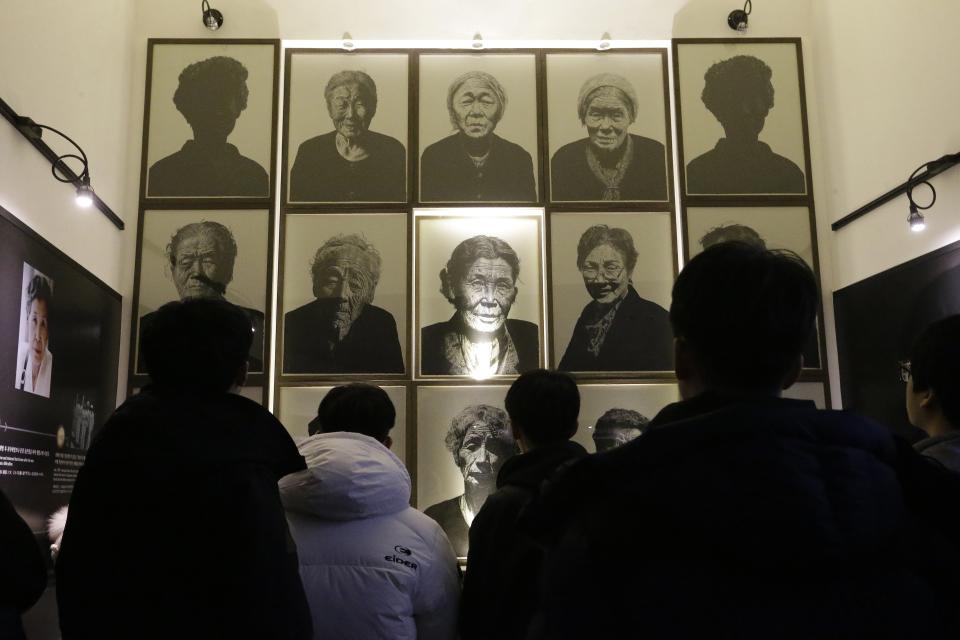 South Korea high school students look at portraits of late former "sex salves" who were forced to serve for the Japanese Army during World War II at the House of Sharing, the home for the living sex slaves, in Gwangju, South Korea, Tuesday, Dec. 29, 2015. A day after trumpeting an "irreversible" settlement of a decades-long standoff over Korean women forced into sexual slavery by Japan's WWII military, there's relief among South Korean and Japanese diplomats, fury among activists and many of the elderly victims and general public indifference in both countries. (AP Photo/Ahn Young-joon)