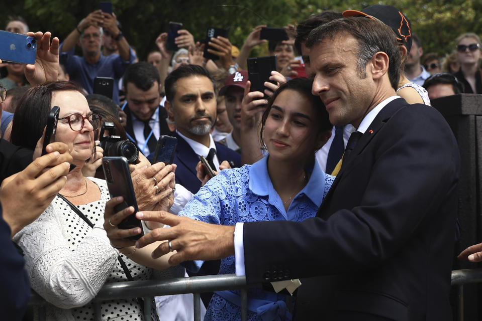 French President Emmanuel Macron makes a selfie with a woman after the annual Bastille Day military parade, in Paris, Friday, July 14, 2023. India is the guest of honor at this year's Bastille Day parade, with Prime Minister Narendra Modi in the presidential tribune alongside French President Emmanuel Macron. (AP Photo/Aurelien Morissard, Pool)