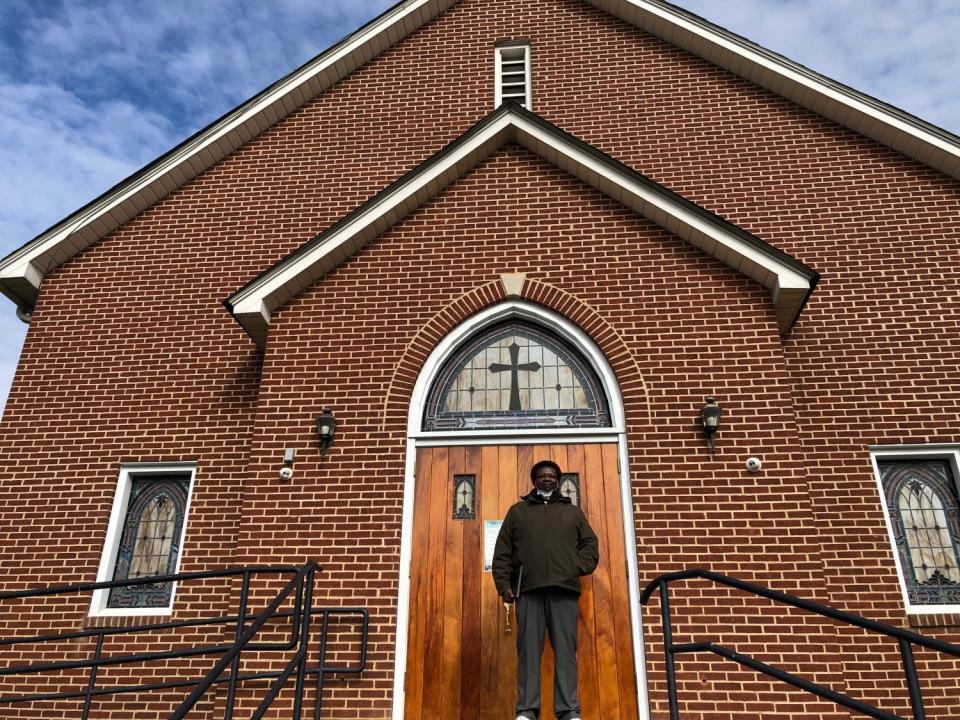 Rev. Aldana Allen stands outside a church door.