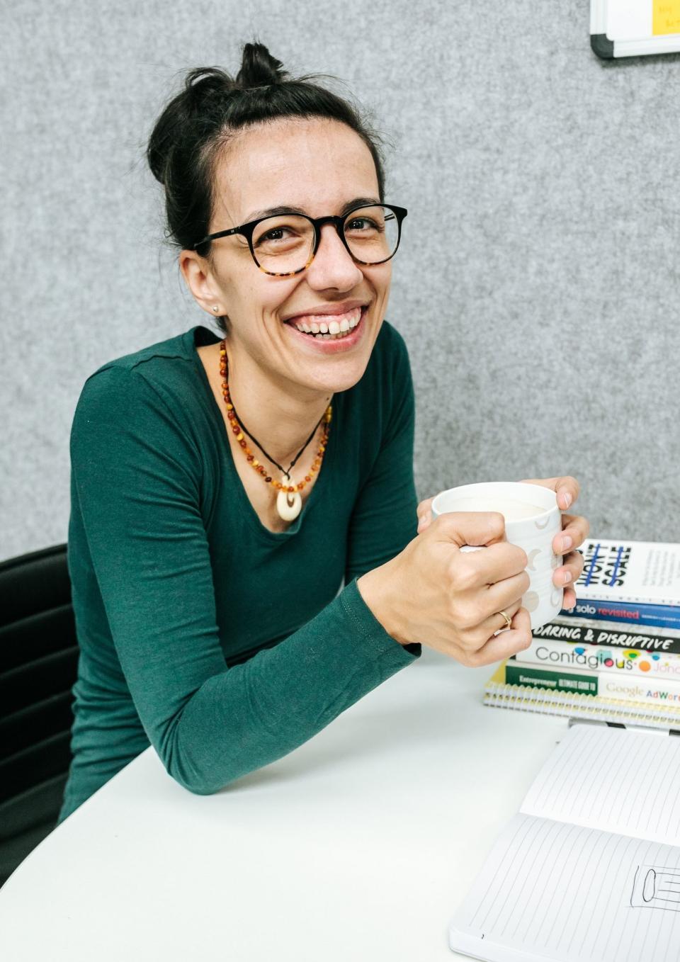 Pictured: Branka Injac Misic seated at office desk with mug in hand, smiling. Image: Supplied