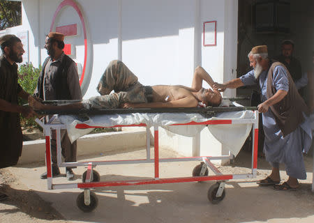 Afghan men carry an injured policeman to a hospital after a blast in Helmand, Afghanistan October 17, 2018. REUTERS/Stringer