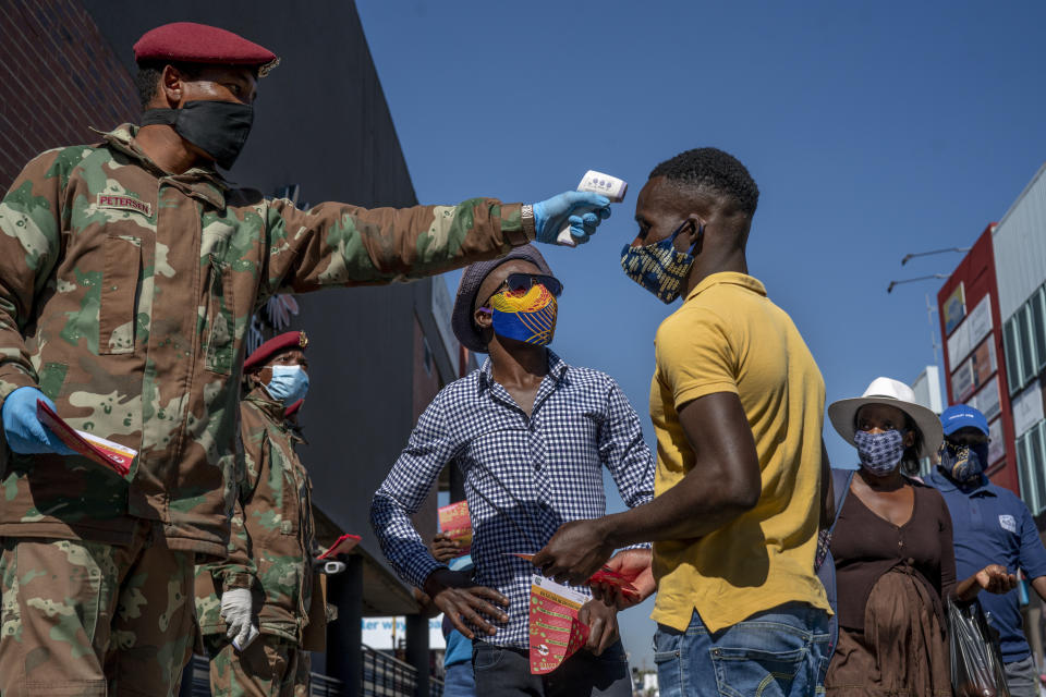 South African National Defense Forces check people's temperature near the Pan Africa taxi rank in Johannesburg's Alexandra township, Wednesday May 20, 2020. South Africa has the continent's highest number of confirmed cases and has eased its restrictions to allow an estimated 1.6 million people to return to work in selected mines, factories and businesses. (AP Photo/Jerome Delay)