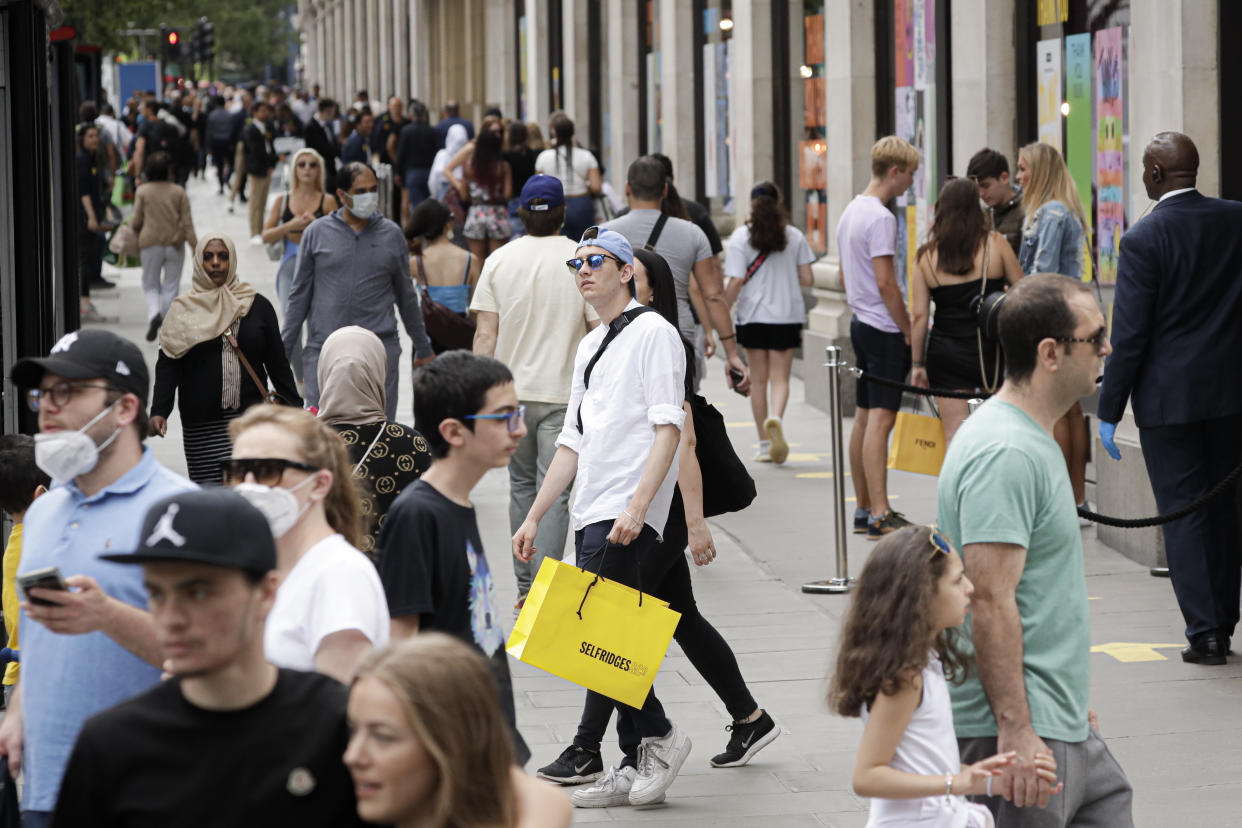 People walk with bags after shopping at the Selfridges department store in London, Monday, June 15, 2020. After three months of being closed under coronavirus restrictions, shops selling fashion, toys and other non-essential goods are being allowed to reopen across England for the first time since the country went into lockdown in March.(AP Photo/Matt Dunham)