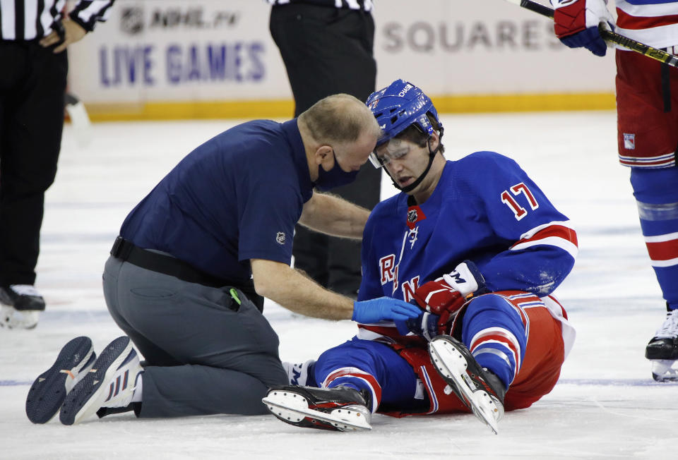 Trainer Jim Ramsay tends to New York Rangers' Kevin Rooney following his collision with New York Islanders' Ross Johnston during the third period of an NHL hockey game Thursday, Jan. 14, 2021, in New York. (Bruce Bennett/Pool Photo via AP)